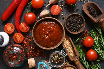 Tomato sauce with spices and chili peppers on a stone table.