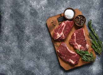 Striploin beef steak on a wooden board with rosemary and salt.