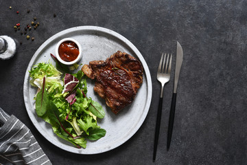 Grilled marbled beef steak with salad in a plate on the kitchen table. With copy space under the text.