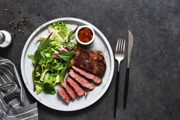  Grilled marbled beef steak with salad in a plate on the kitchen table. With copy space under the text. © zefirchik06
