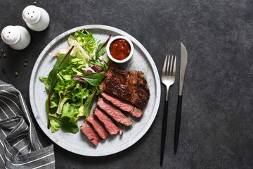 Grilled marbled beef steak with salad in a plate on the kitchen table. With copy space under the text.
