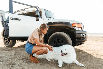 Woman cuddle a dog samoyed outdoors at the beach.