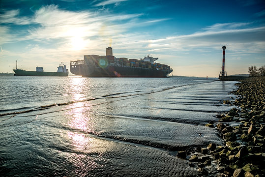 Containerschiff vom Elbstrand in Hamburg aus gesehen im Winter bei sch&ouml;nem Wetter und blauem Himmel