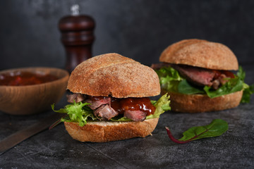 Bun with beef, salad and sauce. Hamburger.