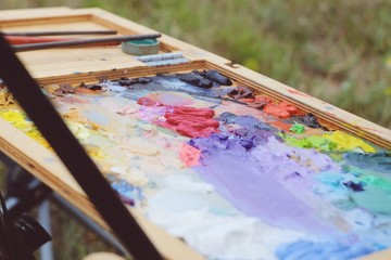 Close up mixing oil paints on the palette. Colorful workplace of the artist with oil paints. Oil...