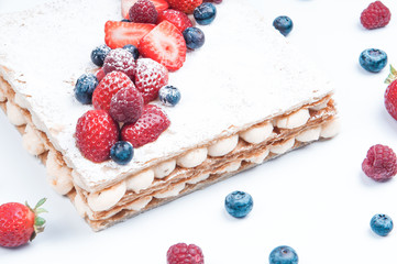 Beautiful puff pastry cake decorated with berries. Close-up of appetizing refreshing dessert with berries around. Bakery shop concept