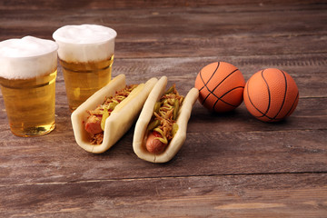 Grilled hot dogs with mustard and ketchup on the table with draft beer. Television watching...