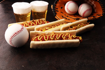 Grilled hot dogs with mustard and ketchup on the table with draft beer. Baseball party food with balls for the playoffs