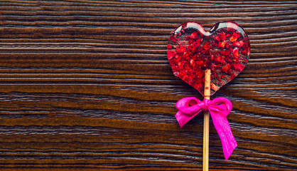 Red heart-shaped candy. Valentines day greeting card. Handmaded candy heart with strawberries and cranberries, on wooden table. Top view with copy space