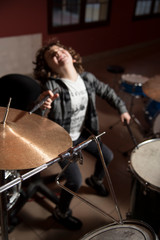 Fototapeta na wymiar Curly-haired boy and gray shirt of shirtmakers playing drums like a pro. Fun and passion playing music