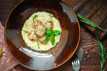 Beef meatballs with risotto in cream sauce in a plate on a wooden background. Italian cuisine rustic style