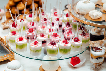 Cakes and berries in the candy bar. Wedding candy bar table. Cakes and other sweets. Sweet table for birthday. Candy bar with a lot of different candies and sweet cakes.