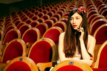 portrait of a pretty girl hipster in a movie theater posing in fashion style, dreaming alone