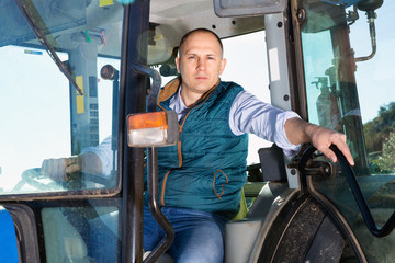 Portrait of handsome man working on farm tractor in vineyard