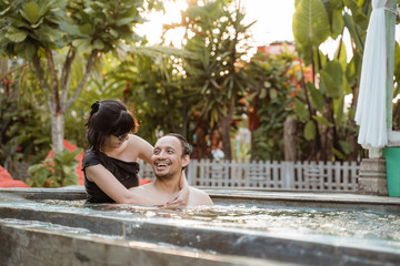 Asian couple relaxing in a swimming pool at holiday together