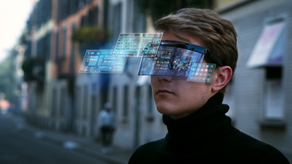 An young man is using futuristic innovative technology vr mask with augmented reality anonymous holograms in a city center. Concept of future,innovation, immersive technology, gaming,virtual reality