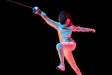 Attacking. Teen girl in fencing costume with sword in hand isolated on black background, neon light. Young model practicing and training in motion, action. Copyspace. Sport, youth, healthy lifestyle.