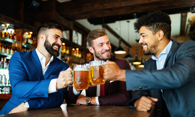 Young businessmen are drinking beer, talking and smiling while resting at the pub