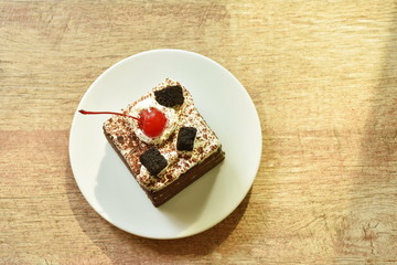  black fotest cake with cream topping cherry on plate