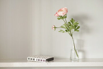 beautiful spring flower in a vase and a diary on a shelf, interior on a sunny day