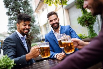 Meeting with the best friends. Happy young business men talking and drinking beer in a pub