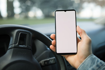 Hand holding smartphone with blank display in a car