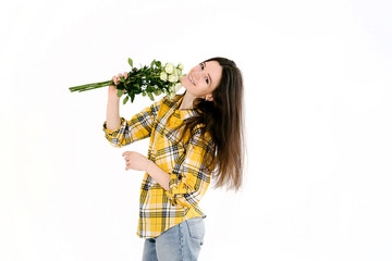 Beautiful brunette woman in a yellow shirt on a white background in the hands of white flowers. The concept of spring and happiness