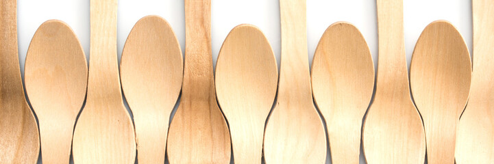 Wooden spoons aligned on white panoramic background, plastic free, environment friendly disposable...