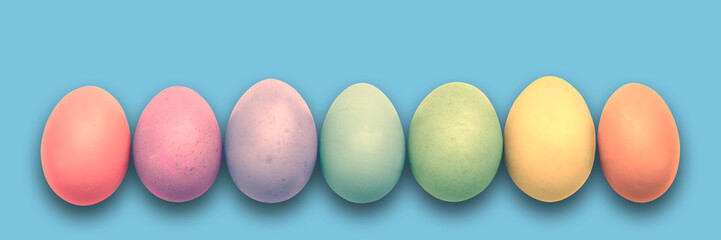 Pastel painted Easter eggs aligned in a row on blue panoramic background, Easter web banner