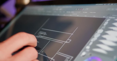 An architect sketching and drafting out blueprints or concept art for a building project on a digital graphic tablet in a design studio.