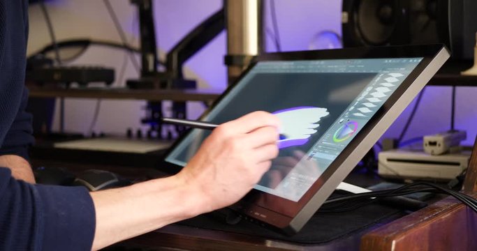 A freelance digital artist or designer sketching and painting in brushstroke with a drawing graphic tablet and pen in an art studio.