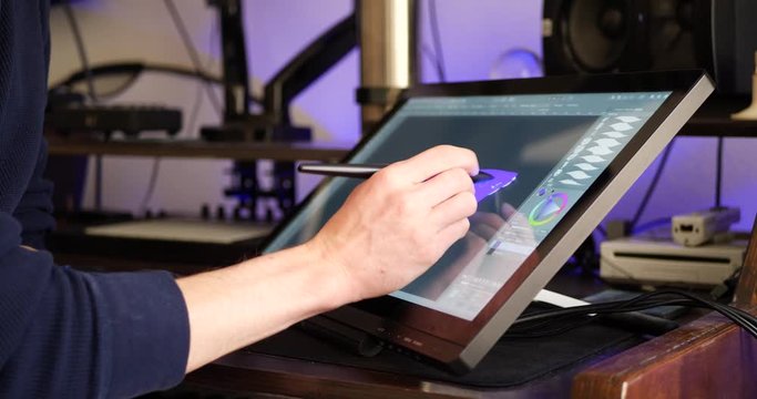 A freelance digital artist or designer sketching and painting in brushstroke with a drawing graphic tablet and pen in an art studio.