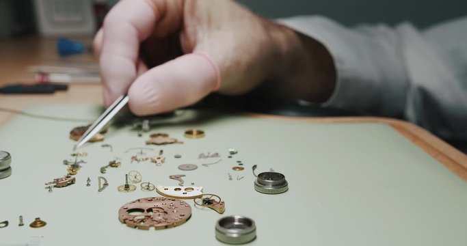 A watchmaker putting screws into a metal screen container for cleaning - close up