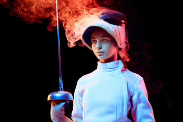Pride. Teen girl in fencing costume with sword in hand isolated on black background, neon lighted...