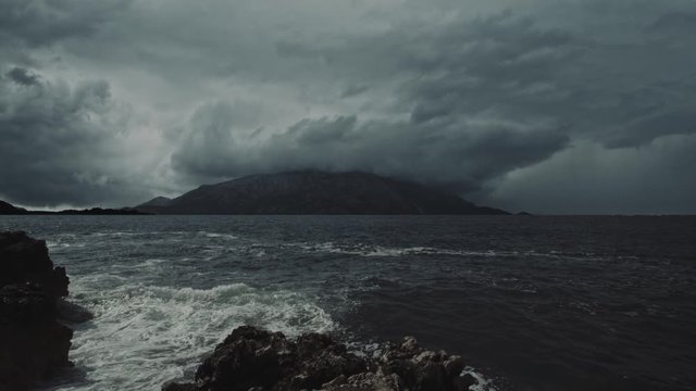 Stormy waves and dramatic storm clouds over a distant, dark, lonely island. Cinematic, filmic, fantasy scene. Montenegro, September.