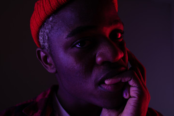 Closeup portrait of a black american man with big lips biting his finger in neon light