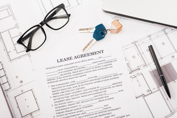 top view of document with lease agreement lettering near glasses, blueprints and keys on desk