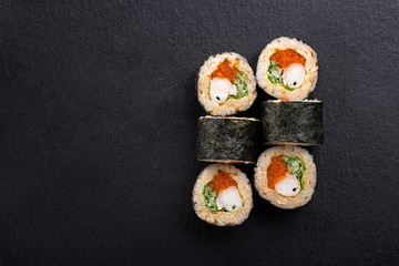 Sushi Rolls with shrimp on a dark background. Japanese traditional roll with prawn. Sushi set on a stone plate and dark concrete background. Sushi roll set and chopsticks. Fresh Japanese cuisine. asia