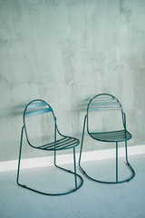 Two metal chairs on gray background. Loft style in the interior.