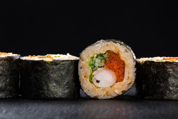 Sushi Rolls with shrimp on a dark background. Japanese traditional roll with prawn. Sushi set on a stone plate and dark concrete background. Sushi roll set and chopsticks. Fresh Japanese cuisine. asia
