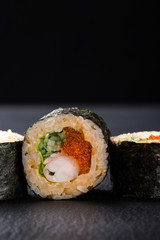 Sushi Rolls with shrimp on a dark background. Japanese traditional roll with prawn. Sushi set on a stone plate and dark concrete background. Sushi roll set and chopsticks. Fresh Japanese cuisine. asia
