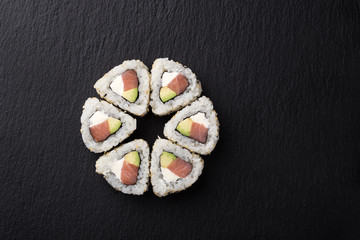 Sushi Rolls with tuna on a dark background. Japanese traditional roll with tuna. Sushi set on a stone plate and dark concrete background. Sushi roll set and chopsticks. Fresh Japanese cuisine. asian f