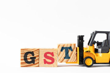 Toy forklift hold wood letter block T to complete word GST (Abbreviation of Goods and Service Tax) on white background
