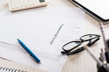 selective focus of paper with commercial lease lettering, pen, calculator and glasses on desk