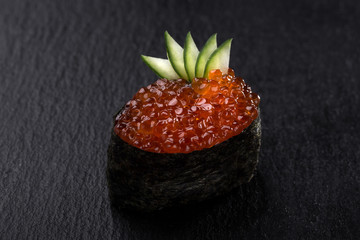 Gunkans with caviar on a dark background. Close up view on gunkan sushi with caviar on dark stone background. Fresh Japanese cuisine. asian food. Sushi image for menu. sushi with red caviar. 