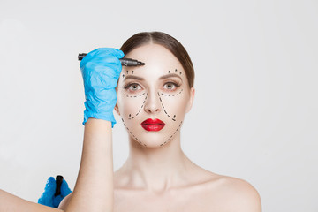 Facial cosmetic plastic surgery. Doctor surgeon hand in glove draw wrinkle lines on Woman face...