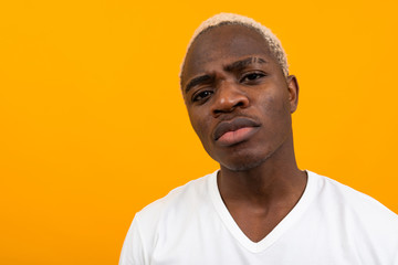 Closeup portrait of a charming honest handsome black blond African man on an orange background
