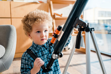 smart and curly child looking at telescope