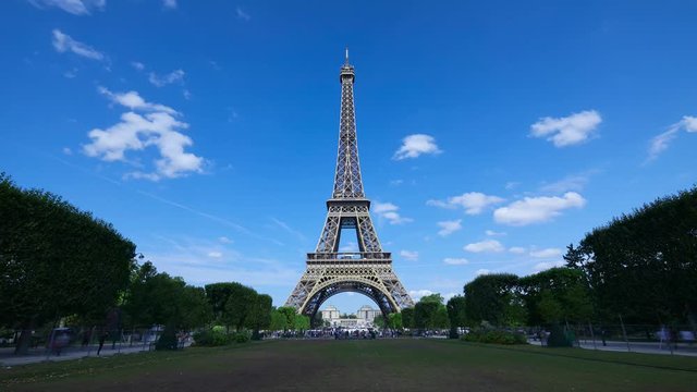 Eiffel tower time lapse, sunny summer day with blue sky and green Field of Mars in Paris