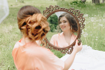 beautiful girl in a bathrobe with a bouquet of flowers on nature in summer on a background of green leaves